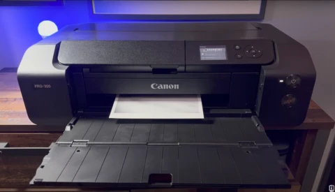 Canon PRO-500 large-format printer with open output tray on wooden desk.