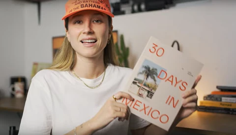 Woman holding a handmade sign reading "50 DAYS IN MEXICO" indoors.