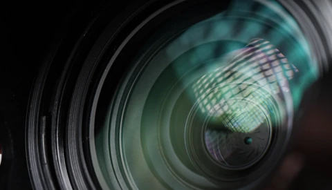 Close-up view of a wide-angle lens showing internal glass elements and aperture blades with circular layering effect.
