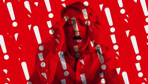 Person's face overlaid with red and gray geometric shapes against a bright red background with white exclamation marks and circles.