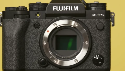 Fujifilm X-T5 mirrorless camera body against yellow background.
