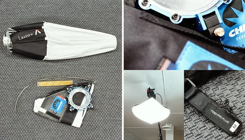 Photography lighting equipment including a softbox, LED panel, reflector, and cables laid out on a gray surface.