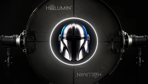 Mandalorian helmet centered in glowing white circle with professional lighting rigs on either side.