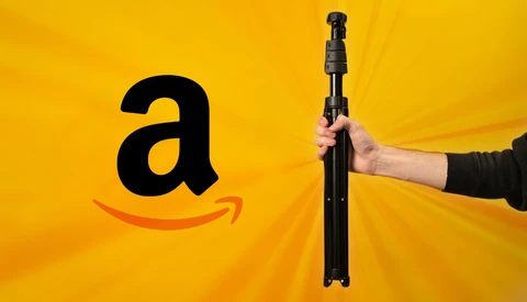 Hand holding an extended monopod or selfie stick against a bright yellow background next to Amazon logo.