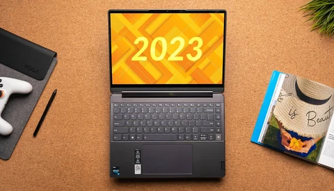 Laptop displaying "2023" on yellow geometric background, surrounded by creative workspace items.