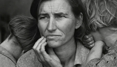 Man with hand to face surrounded by children in close, intimate black and white portrait.