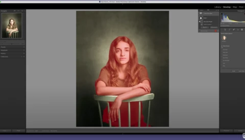 Portrait of a woman with long red hair seated in a red chair against a dark, textured background.