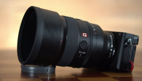 Sony G-series telephoto lens with lens hood attached mounted on mirrorless camera body.