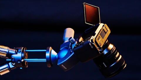 Professional cinema camera rig with blue and gold lighting equipment against dark background.