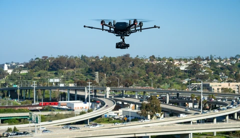 Drone hovering above a multi-level highway interchange with dense urban development in the background.