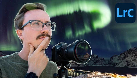 Photographer holding Canon mirrorless camera with telephoto lens, gazing upward at aurora borealis overhead.