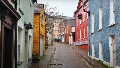 Narrow street lined with colorful historic buildings in various pastel hues including green, yellow, red, and blue.