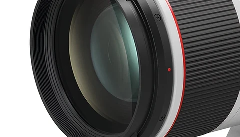 Close-up of a telephoto lens showing glass elements and red accents on the barrel.