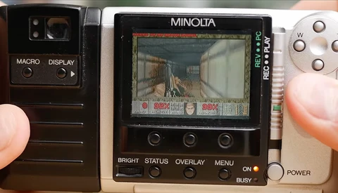 Three vintage Minolta cameras displayed side by side showing LCD screens and control buttons.