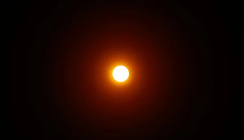 Bright sun centered against a dark sky with warm orange and yellow glow radiating outward.
