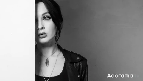 Woman's face in profile against a plain wall, rendered in high-contrast black and white.