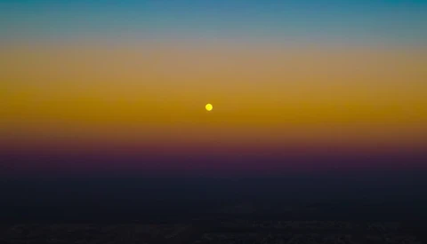 Sun positioned low on the horizon during golden hour with deep blue and purple tones in the sky.