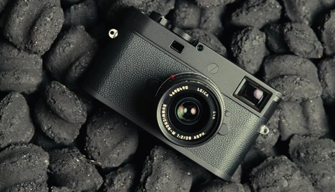 Rangefinder camera with textured grip and fixed lens on a cobblestone surface.