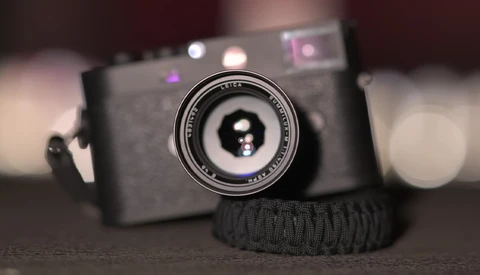 Rangefinder camera with prime lens mounted, displayed with shallow depth of field against blurred background.