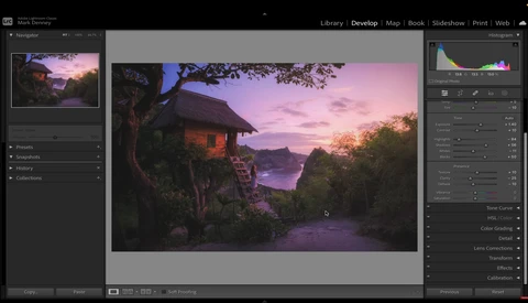 Tropical sunset landscape with thatched-roof structure framed by tree branches overlooking water.
