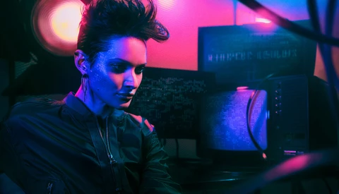 Person working at a computer workstation lit with vibrant pink and blue neon lights.