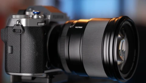 Rangefinder camera with attached lens against blurred background.