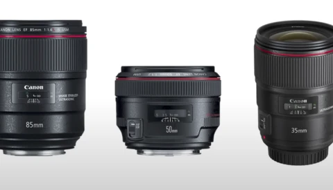 Three Canon prime lenses: 85mm f/1.4, 50mm f/1.8, and 35mm f/1.4 arranged side by side against a gray background.