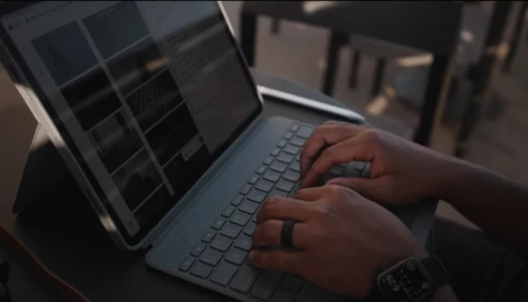 Hands typing on a laptop keyboard in outdoor sunlight with warm golden-hour lighting.