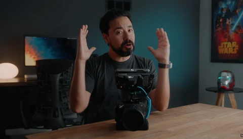 Content creator gesturing while holding a mirrorless camera during a discussion or tutorial.