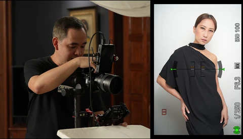 Photographer adjusting a camera mounted on a studio rig while monitoring a portrait subject on a display screen.