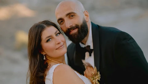 Couple in formal attire posing together outdoors at golden hour.