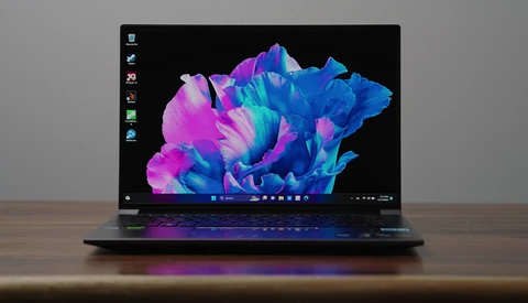 Laptop displaying vibrant blue and magenta abstract 3D rendered shapes on black background.