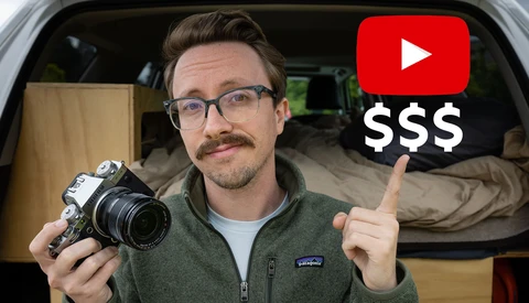 Man holding vintage film camera inside a van, pointing at YouTube and dollar sign graphics overlay.