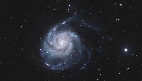 Spiral galaxy with bright central core and sweeping blue arms against starfield.