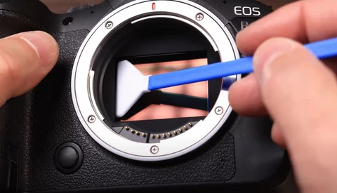 Cleaning the mirror and sensor of a Canon EOS camera with a blue swab and sensor cleaning pen.