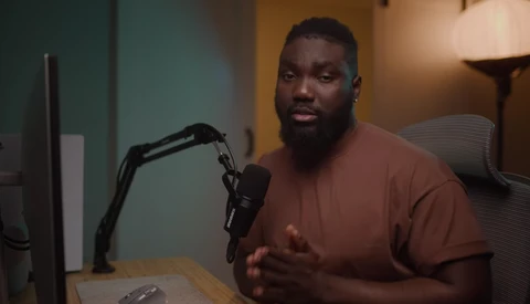 Man speaking into a microphone at a desk during a podcast or interview recording.
