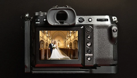Mirrorless camera displaying a wedding ceremony photograph on its rear LCD screen.