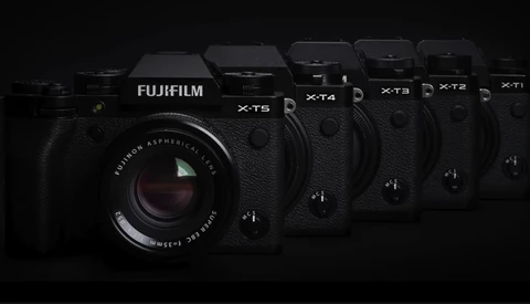 Fujifilm X-series mirrorless cameras arranged in a line, featuring the X-T5 prominently in the foreground with its lens visible.