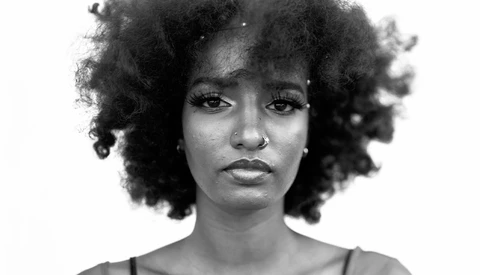 Black and white portrait of a woman with voluminous natural curly hair against a plain background.