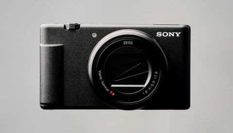 Sony mirrorless camera body with Zeiss lens shown against neutral gray background.