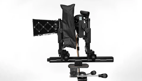 Overhead view of a camera rig with articulating arms, mounting plate, and control handle on white background.
