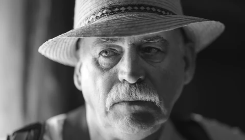 Black and white portrait of an older man wearing a wide-brimmed straw hat with a dark band.