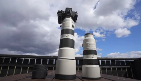 Two telephoto lenses with black and white striping displayed on a rooftop with a camera mounted on the taller lens.