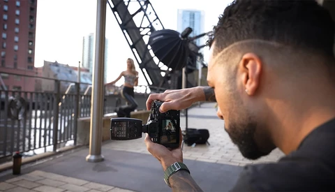 Videographer filming a skateboarder on an urban bridge with a cinema camera.