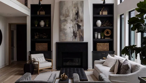 Modern living room with black fireplace surround flanked by shelving, neutral seating, and abstract artwork above.