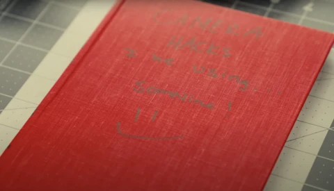 Red hardcover book with embossed text on cover, photographed at an angle on a gridded surface.