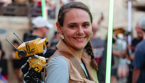 Woman holding yellow and black robot or mechanical device with antennae at an indoor event.