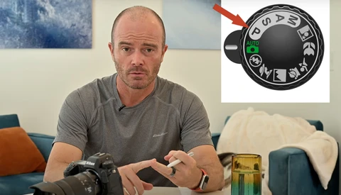 Photographer holding a camera body while examining a vintage lens with an aperture ring detail highlighted.