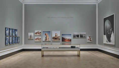 Gallery wall displaying framed photographs of varying sizes arranged symmetrically around a central display case.