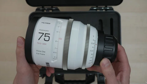 Hands holding a Viltrox 75mm f/1.2 lens with white barrel and focus ring, displayed in black carrying case.
